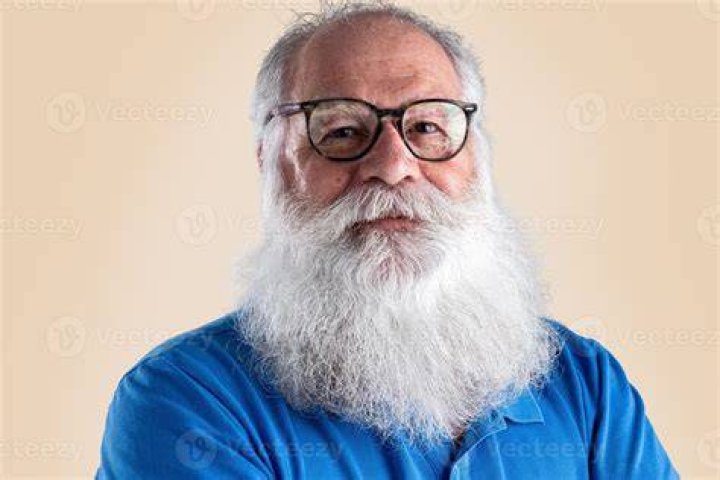 a man with a beard wearing a gray suit and grey shirt is looking at the