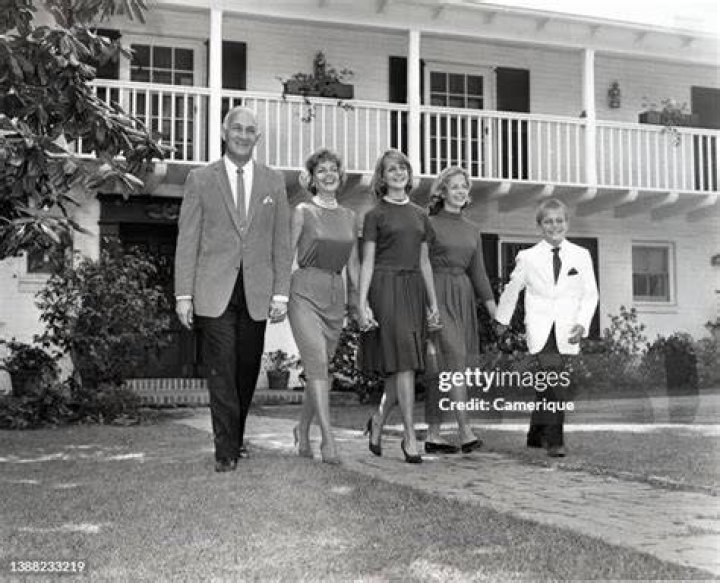 Tom Harmon family walking in front of their house holding hands